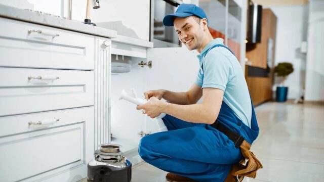 smiling-male-plumber-in-uniform-holds-drain-pipe-resize.jpg